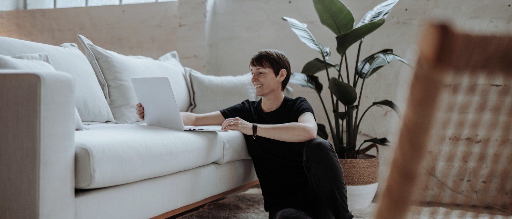 Alexandra Sackmann am Laptop, auf dem Boden neben einem Sofa