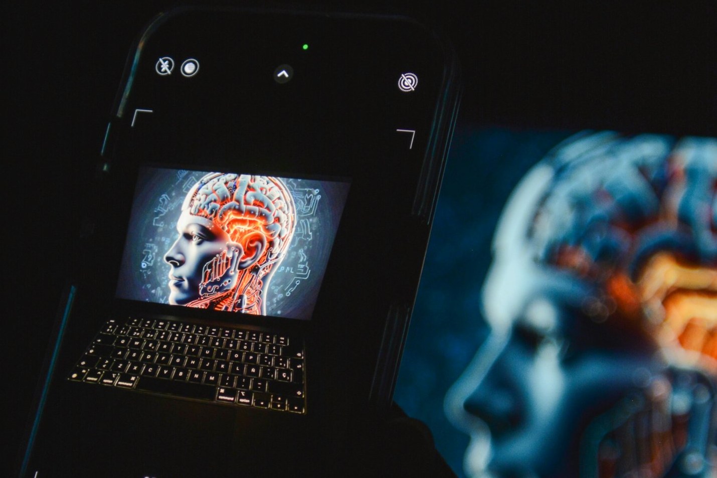 Smartphone fotografiert eine KI Darstellung eines Kopfes auf einem Laptop